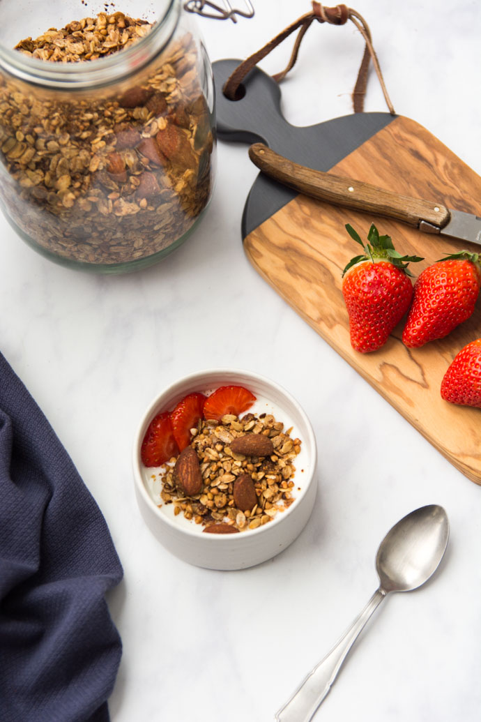 Un petit bol de granola maison, accompagné de fraises et de yaourt à la noix de coco