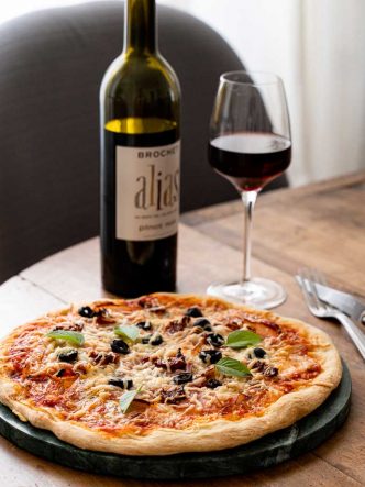 Recette facile et maison de pizza au speck, base tomates olives & câpres, mozzarella et basilic - accompagné d'un délicieux vin de Loire 100% Pinot Noir Amplidae ALIAS