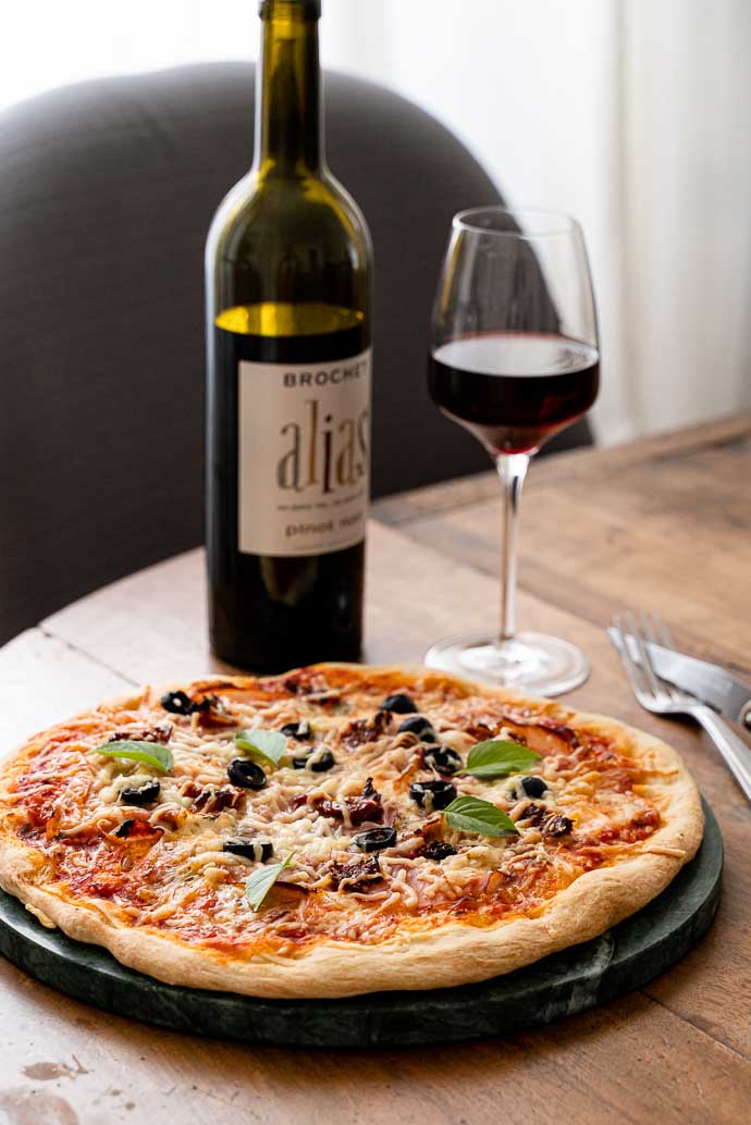 Recette facile et maison de pizza au speck, base tomates olives & câpres, mozzarella et basilic - accompagné d'un délicieux vin de Loire 100% Pinot Noir Amplidae ALIAS