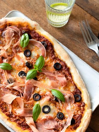 Recette italienne, facile de pizza maison au pesto rosso, prosciutto, mozzarella & olives