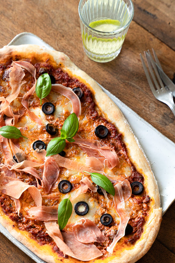 Recette italienne, facile de pizza maison au pesto rosso, prosciutto, mozzarella & olives